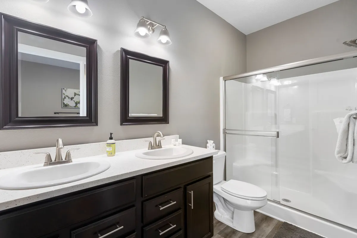 A modern ensuite bathroom with dual sinks, expansive mirrors, and a spacious shower area. The soft lighting and clean lines evoke a sense of relaxation and indulgence, ideal for morning and evening routines.