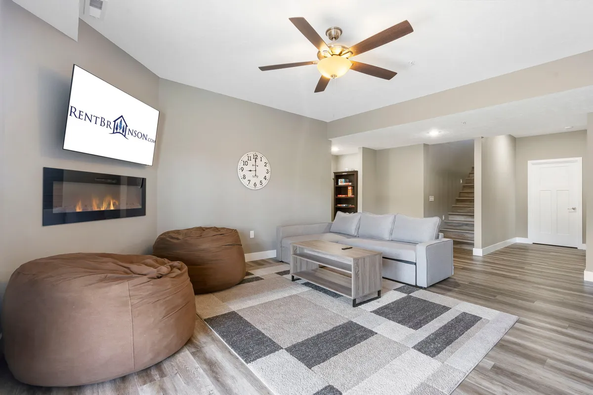 A cozy second living area with a modern sofa, several bean bag chairs, a fireplace, and a TV. The arrangement is designed for relaxed gatherings, movie nights, and downtime with family or friends.