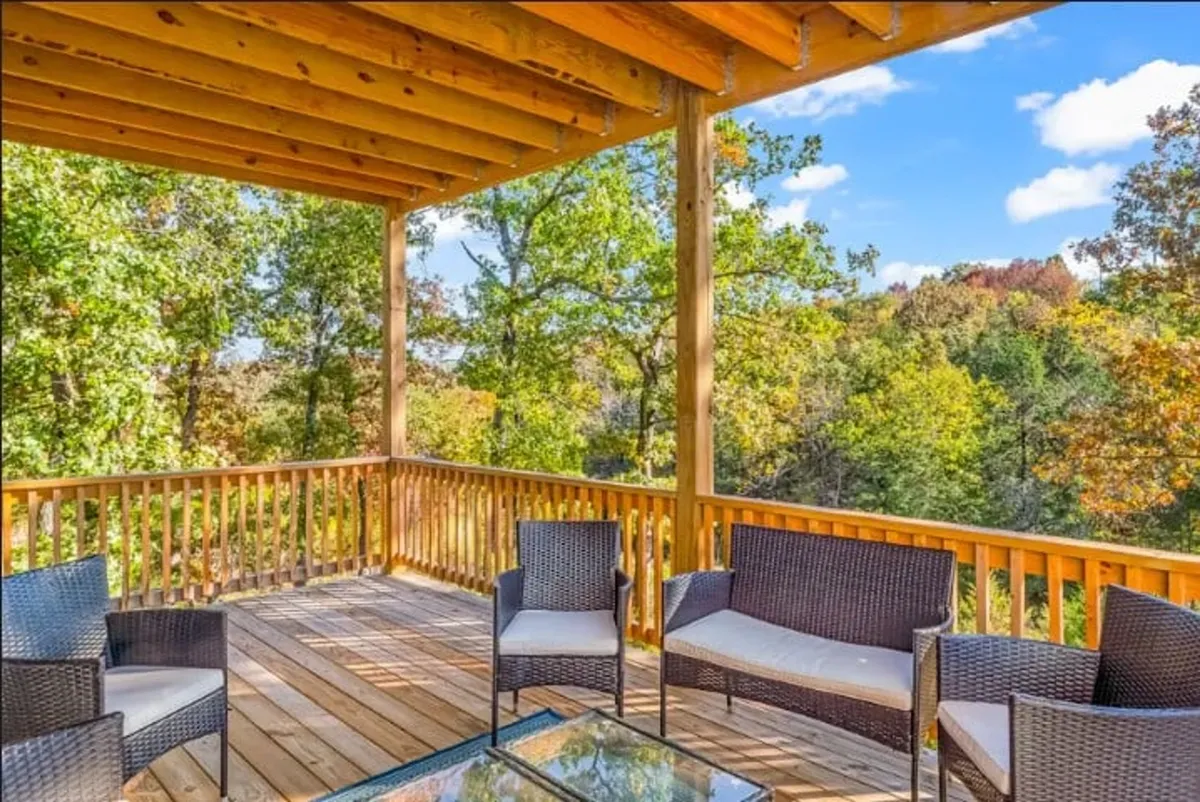 A serene outdoor deck with comfortable seating set against a backdrop of natural woodland. The wooden deck invites guests to sit back, relax, and enjoy quiet moments amidst the trees, perfect for morning coffee or evening chats.