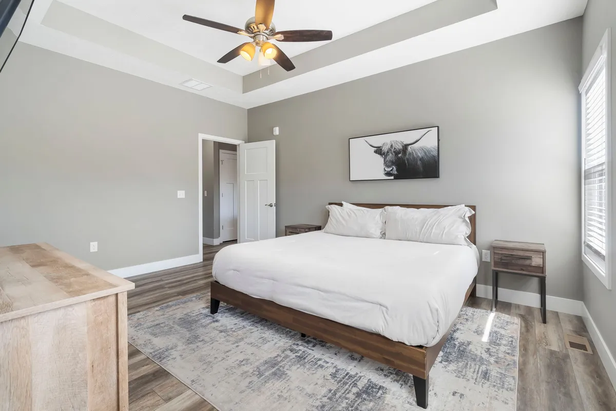 A serene bedroom with a plush bed, nightstands, and calming artwork on the wall. The room is bathed in gentle natural light, and the overall ambiance is peaceful and inviting, suggesting a luxurious private retreat.