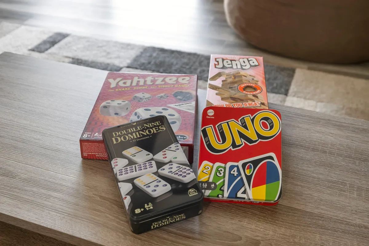 A close-up of a wooden table scattered with various board games and game boxes, suggesting the excitement of friendly competition and group activities.