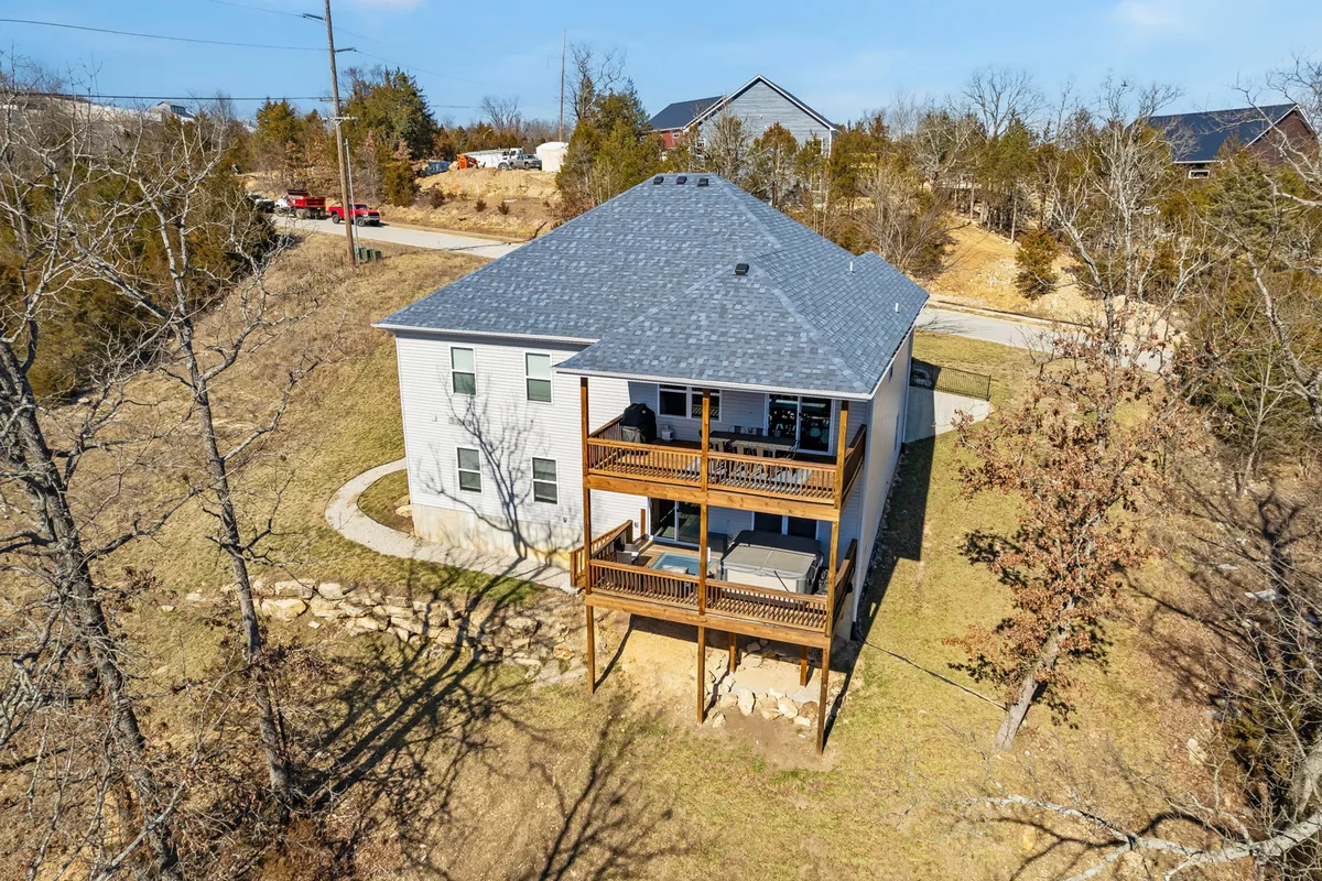 An inviting exterior view of the Adventure Lodge, featuring its balconies and the surrounding landscape. The image captures the house as a central hub for family and group gatherings, with the outdoor spaces suggesting opportunities for grilling, al fresco dining, and relaxation with nature all around.